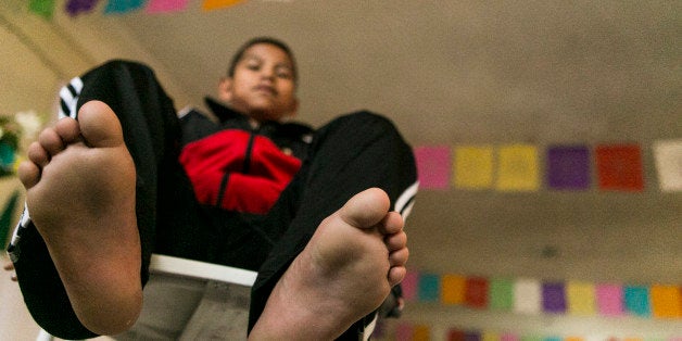 Malquiades Ramirez de Jesus, 10 from El Rastrojo village near San Juan Copala, Oaxaca takes his tennis shoes off, during an appearance with the Triqui kids basketball team, made up of children from the mountainous region of the Mexican state of Oaxaca, during a news conference at the community center of Casa Oaxaca in Los Angeles Wednesday, Dec. 18, 2013. The team has been dubbed "the barefooted giants of the mountains'' after learning how to play basketball barefooted and win international matches. (AP Photo/Damian Dovarganes)