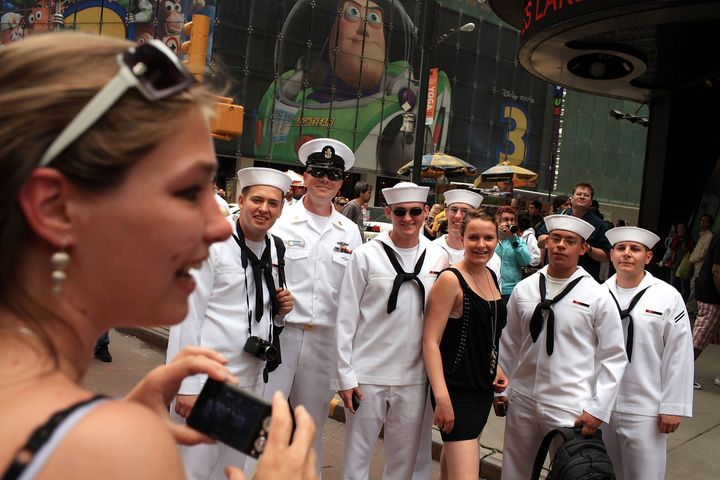 NEW YORK - MAY 28: Women pose for pictures with members of the United States Navy in Times Square as part of Fleet Week festivities May 28, 2010 in New York City. Fleet Week, which has been held in New York since 1984, brings thousands of military members to the city where they engage the public with numerous activities and demonstrations, tours and contests. Fleet Week will conclude on June 2nd. (Photo by Spencer Platt/Getty Images)