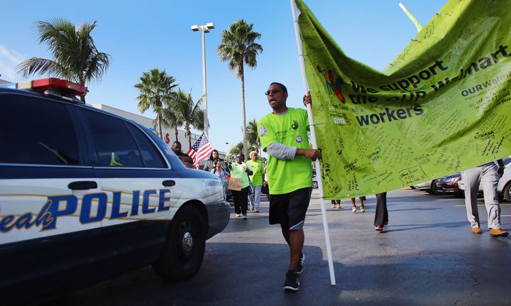 HIALEAH, FL - DECEMBER 14: A police car maneuvers between protesters as they participate in a 'Global Day' of action against Walmart on December 14, 2012 in Hialeah, Florida. The protesters in partnership with the global union federation UNI, the union-affiliated group Making Change at Walmart joined others around the world to among other things call for an end to alleged retaliation against US Walmart worker activists. (Photo by Joe Raedle/Getty Images)