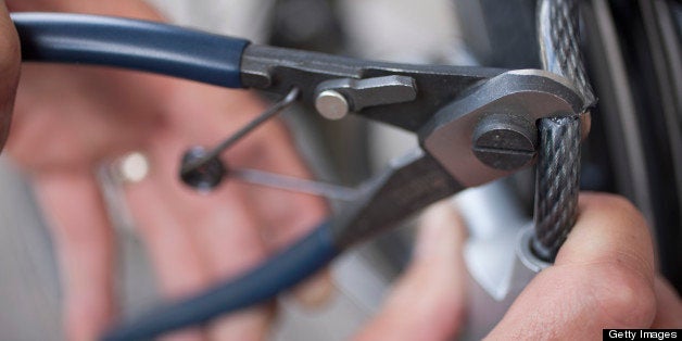 Germany, Bavaria, Munich, Mature man cutting bicycle lock with wire cutters