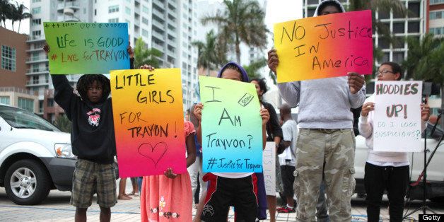 MIAMI, FL - JULY 14: Demonstrators hold signs in front of the Torch of Friendship in downtown Miami a day after the verdict to the George Zimmerman murder trail on July 14, 2013 in Miami, Florida. A jury found neighborhood watch volunteer, George Zimmerman not guilty of shooting and killing 17-year-old Trayvon Martin after an altercation in February 2012. (Photo by Angel Valentin/Getty Images)