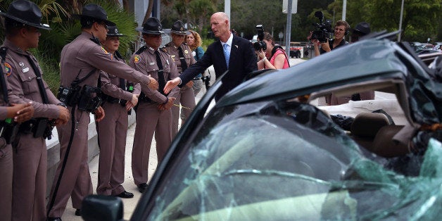 MIAMI, FL - MAY 28: Florida Governor Rick Scott shakes hands with Florida Highway patrol officers near a wrecked car that is on display after he signed Florida Senate Bill 52, legislation to ban texting while driving during a visit to Alonzo and Tracy Mourning Senior High School on May 28, 2013 in Miami, Florida. The bill prohibits a person from manually typing or entering multiple letters, numbers, symbols or other characters into a wireless communications device while driving. This includes text messaging, emailing and instant messaging through smart phones. (Photo by Joe Raedle/Getty Images)