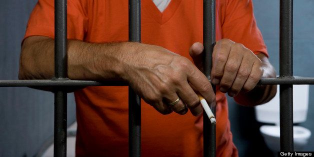 A prisoner smoking a cigarette in his prison cell