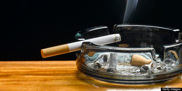 Burning cigarette in ashtray on table