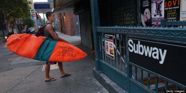 392748 01: Surfer Paul Treacy carries his surfboard to the New York City Subway August 2, 2001 as he starts his hour-long trek from his Manhattan apartment to Rockaway Beach. Treacy, an Irish native who has traveled the globe in search of perfect waves, is part of a small number of dedicated New York City surfers who ride the subway daily to satisfy their wave-riding addictions. (Photo by Spencer Platt/Getty Images)