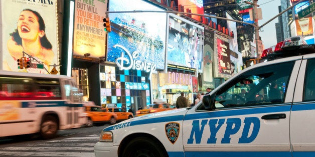 Street scene from Broadway at Times Square at twilight - NY Police Department car on duty in the foreground with traffic and numerous illuminated billboards in the background.