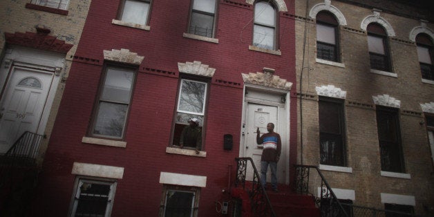 NEW YORK, NY - DECEMBER 06: Residents stand outside their home as community activists and over two hundred members of the Occupy Wall Street movement march in the impoverished community of East New York to draw attention to foreclosed homes in the community on December 6, 2011 in the Brooklyn borough of New York City. The group said they would occupy a home and would hand the property over to a homeless family. In what organizers are describing as a 'new frontier' for the movement, thousands of other Occupy Wall street protesters around the country participated in similar actions. (Photo by Spencer Platt/Getty Images)