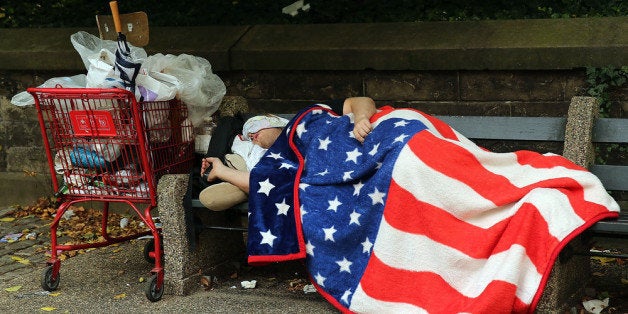 NEW YORK, NY - SEPTEMBER 10: A homeless man sleeps under an American Flag blanket on a park bench on September 10, 2013 in the Brooklyn borough of New York City. As of June 2013, there were an all-time record of 50,900 homeless people, including 12,100 homeless families with 21,300 homeless children homeless in New York City. (Photo by Spencer Platt/Getty Images)