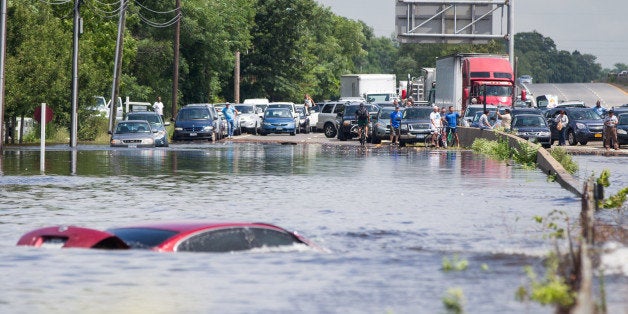 ISLIP, NY - AUGUST 13: People look on as a car remains flooded on Sunrise Highway at Route 111 following heavy rains and fl
