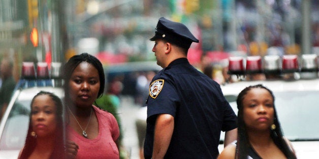 NEW YORK, NY - AUGUST 12: People walk by a New York City police officer in Times Square on August 12, 2013 in New York City.
