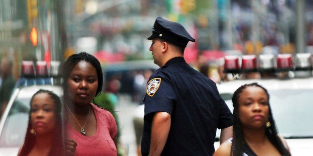 NEW YORK, NY - AUGUST 12: People walk by a New York City police officer in Times Square on August 12, 2013 in New York City. The controversial policy employed by the New York Police Department (NYPD) in high crime neighborhoods known as stop and frisk, has been given a severe rebuke by a federal judge on Monday. U.S. District Court Judge Shira Scheindlin has appointed an independent monitor to oversee changes to the NYPD's stop and frisk tactic's after finding that it intentionally discriminates based on race. Both New York City Mayor Michael Bloomberg and New York City Police Commissioner Raymond Kelly. (Photo by Spencer Platt/Getty Images)