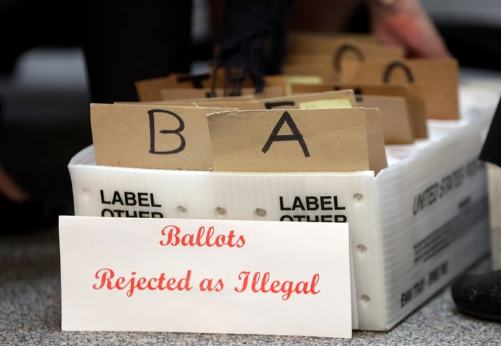 In this Oct. 30 photo, rejected mail-in ballots sit in a box as members of the canvassing board verify signatures on ballots at the Miami-Dade County Elections Department in Florida.