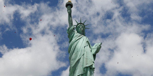 One of three helicopters showeres 1-million rose petals on the Statue of Liberty during a ceremony commemorating the 70th anniversary of the D-Day invasion, on Liberty Island in New York Harbor, Friday, June 6, 2014. (AP Photo/Richard Drew)