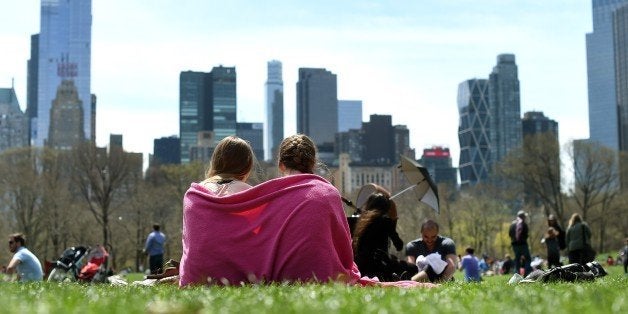 A couple of young girls are wrapped in a blanket on the Sheep Meadow in Central Park April 19, 2015 as New Yorkers flock outside to enjoy the warmer Spring weather. AFP PHOTO / TIMOTHY A. CLARY (Photo credit should read TIMOTHY A. CLARY/AFP/Getty Images)