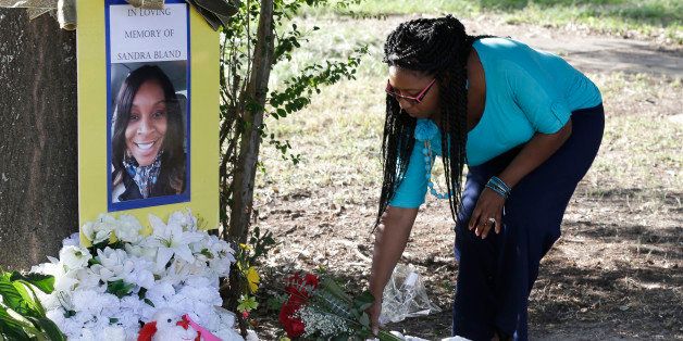 Jeanette Williams places a bouquet of roses at a memorial for Sandra Bland near Prairie View A&M University, Tuesday, July 21, 2015, in Prairie View, Texas. A newly released dashcam video documents how a routine traffic stop escalated into a shouting confrontation between a Texas state trooper and Bland, which led to her arrest. Bland was found hanging in her jail cell three days after the incident. (AP Photo/Pat Sullivan)