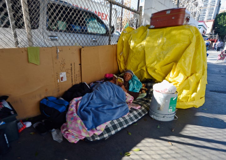 LOS ANGELES, CA - DECEMBER 11: Homeless people from Skid Row are seen on the streets around a construction project where102 prefabricated housing units placed on top of the second floor of Star Apartments are being built December 11, 2012 in Los Angeles, California. The modular homes will become the first multi unit prefabricated homes in Los Angeles for formerly homeless and impoverished people. Despite efforts from the Federal Government and local officials to provide more shelters and beds for homeless people, the number of people living on the streets remained unchanged from January 2011 to January 2012. The number of homeless families increased while the number of veterans on the street decreased. (Photo by Kevork Djansezian/Getty Images)