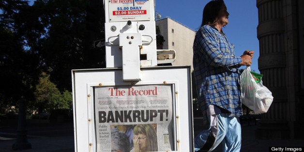 STOCKTON, CA - JUNE 27: A pedestrian walks by a Stockton Record newspaper rack displaying the headline 'Bankrupt!' on June