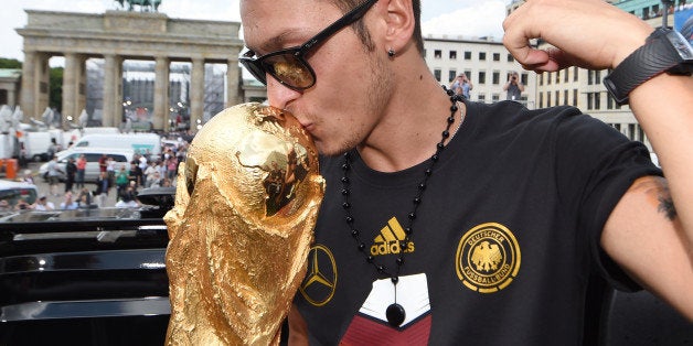 BERLIN, GERMANY - JULY 15: Mesut Oezil celebrates on the open top bus at the German team victory ceremony on July 15, 2014 in Berlin, Germany. Germany won the 2014 FIFA World Cup Brazil match against Argentina in Rio de Janeiro on July 13. (Photo by Markus Gilliar - Pool/Getty Images)