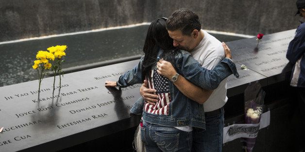 NEW YORK, NY - SEPTEMBER 11: Eileen Esquilin hugs her husband, Joe Irizarry, while mourning the loss of her brother, Ruben Esquilin Jr, during the memorial observances held at the site of the World Trade Center on September 11, 2014 in New York City. This year marks the 13th anniversary of the September 11th terrorist attacks that killed nearly 3,000 people at the World Trade Center, Pentagon and on Flight 93. (Photo by Andrew Burton/Getty Images)