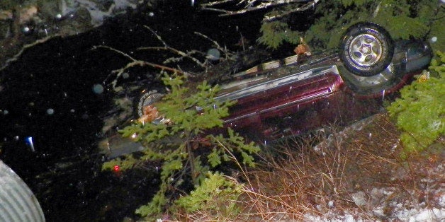 In this Nov. 17, 2014 photo provided by Maine State Police, an SUV rests upside down in water alongside Route 6 in Kossuth Township, Maine, after Stephen McGouldrick lost control of it on the icy road. Police said Leo Moody, of Kingman, Maine, crawled into the SUV and used a knife to cut the straps off a submerged car seat to pull an infant to safety. The infant was taken to Eastern Maine Medical Center for observation. The two other passengers suffered minor injuries and were treated and released from a hospital. (AP Photo/Maine State Police)