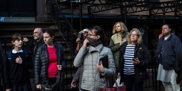 NEW YORK, NY - MARCH 26: Civilians watch firefighters battle a blaze caused by an explosion that forced two buildings to col