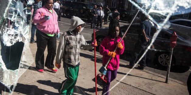 BALTIMORE, MD - APRIL 28: People helping to clean up debris caused by rioting yesterday after the funeral of Freddie Gray are seen in the reflection of a partially destroyed window on April 28, 2015 in Baltimore, Maryland. Gray, 25, was arrested for possessing a switch blade knife April 12 outside the Gilmor Houses housing project on Baltimore's west side. According to his attorney, Gray died a week later in the hospital from a severe spinal cord injury he received while in police custody. (Photo by Andrew Burton/Getty Images)