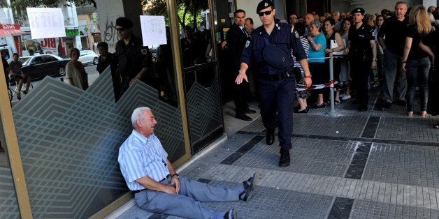 An elderly man is crying outside a national bank branch as pensioners queue to get their pensions, with a limit of 120 euros, in Thessaloniki on 3 July, 2015. Greece is almost evenly split over a crucial weekend referendum that could decide its financial fate, with a 'Yes' result possibly ahead by a whisker, the latest survey Friday showed. Prime Minister Alexis Tsipras's government is asking Greece's voters to vote 'No' to a technically phrased question asking if they are willing to accept more tough austerity conditions from international creditors in exchange for bailout funds. AFP PHOTO /Sakis Mitrolidis (Photo credit should read SAKIS MITROLIDIS/AFP/Getty Images)