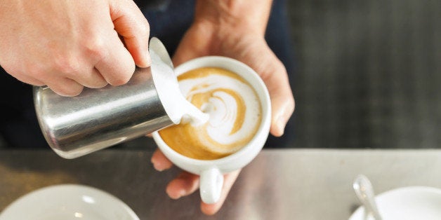 Barista making cappuccino in his coffeeshop or cafe, close-up