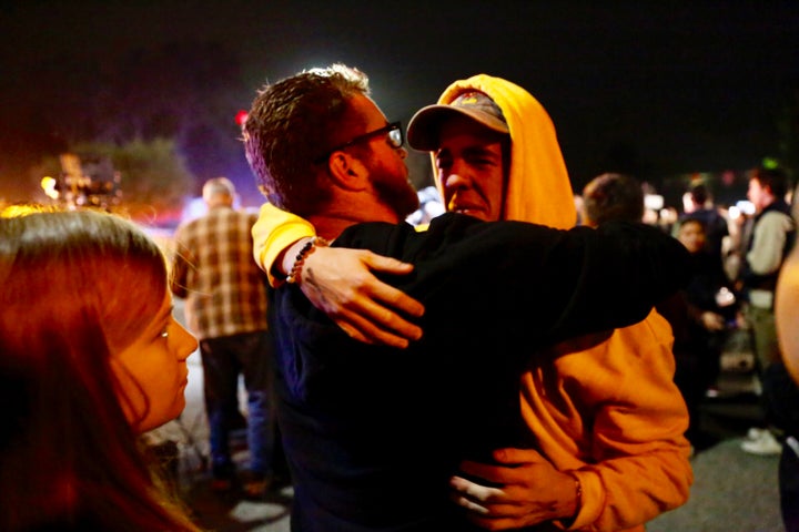 Holden Harrah, 21, (right), who witnessed the shooting at Borderline Bar & Grill late Wednesday, hugs family and friends.