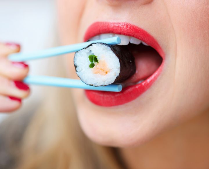 woman eating sushi with chop sticks , close up