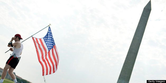 A runner carrying a US flag runs past the Washington Monument on May 28, 2012 in Washington, DC. People around the United Sta