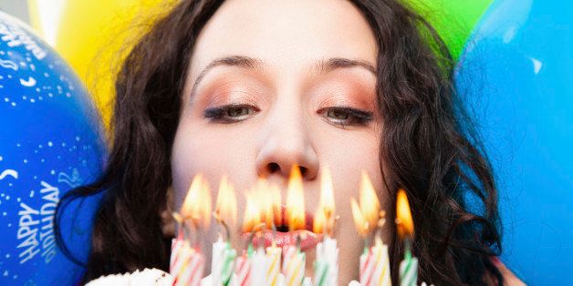 Happy young woman celebrating a Birthday and she is ready to put out the candles on cake.