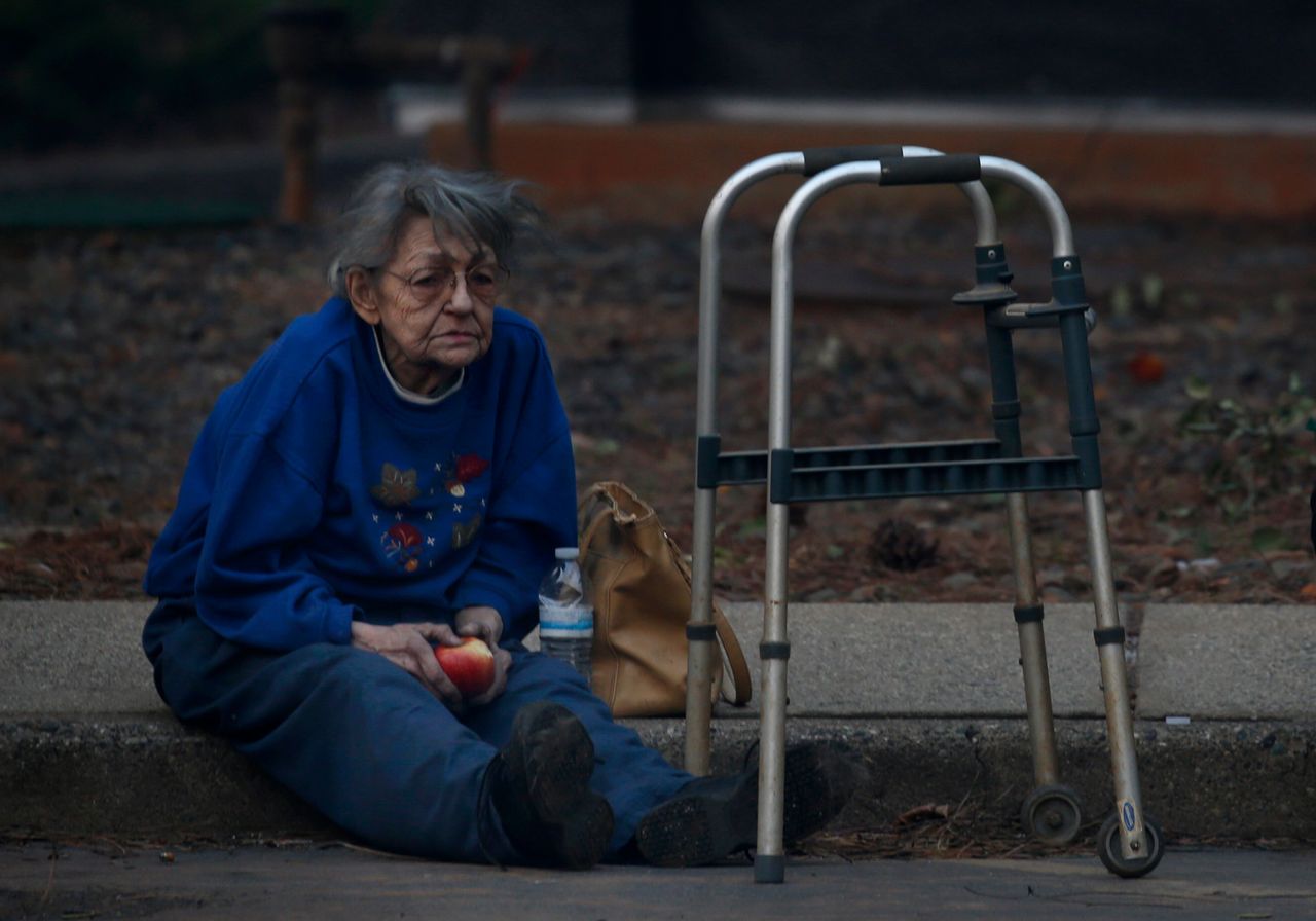 Juanita McLish sits on a curb after she and her husband lost their home in the Campfire blaze raging through Paradise, Calif., on Nov. 8.