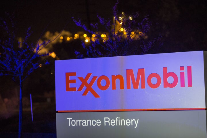 Flames from flaring glow behind the Exxon Mobil logo at a refinery in California.