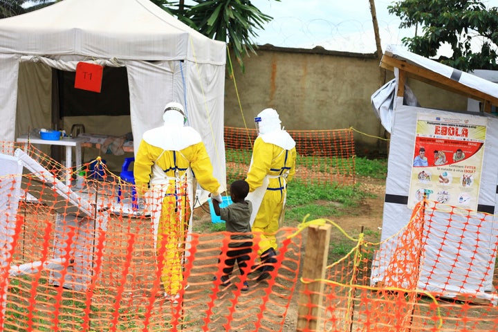 In this photo taken Sunday, Sept 9, 2018, health workers walk with a boy suspected of having the Ebola virus at an Ebola treatment center in Beni, Eastern Congo.