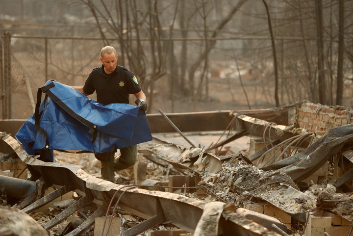 An official searches the remains of a building in Paradise, CA