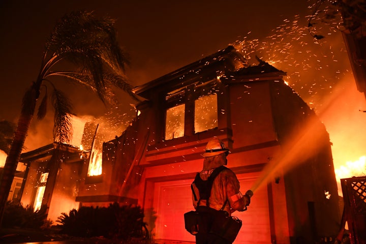 A firefighter battles a house fire as the Woolsey Fire burns in Oak Park, a community in Southern California, early Friday morning.