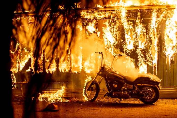 A structure and a motorcycle burn at an RV park during the Woolsey fire in Malibu, California, Nov. 10, 2018.