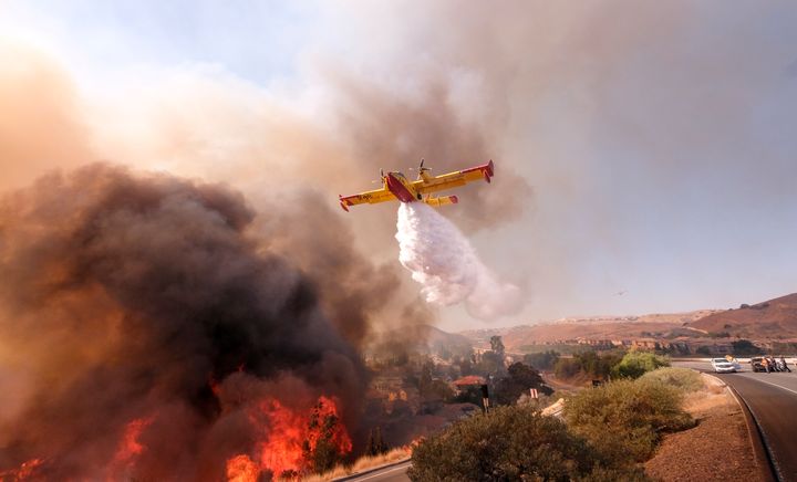 An air tanker drops water on a fire along the freeway in Simi Valley