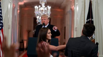 President Donald Trump watches as a White House aide reaches to take away a microphone from CNN journalist Jim Acosta during a news conference in the East Room of the White House, Wednesday, Nov. 7, 2018, in Washington. (AP Photo/Evan Vucci)