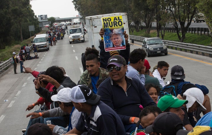 A Central American migrant holds a sign with a message that reads in Spanish: "No to the wall Trump", while hitching a ride o