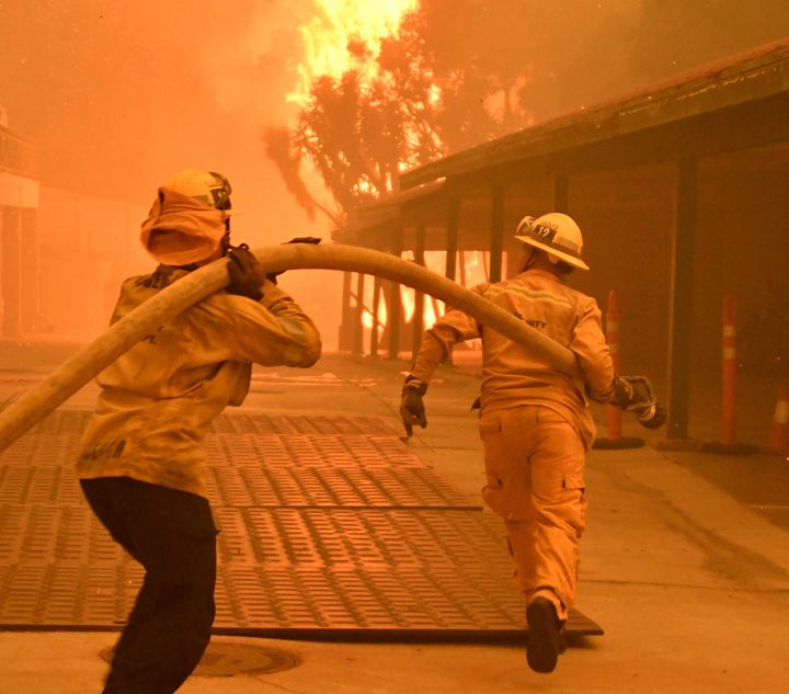 Firefighters prepare to hose down flames as the Woolsey fire consumes a condo unit in Malibu, California, on Nov. 9, 2018.