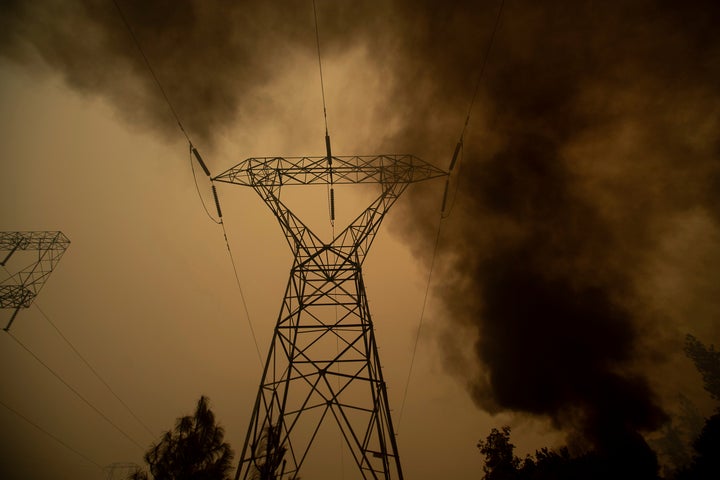 This type of power infrastructure hasn't been properly maintained by PG&E, the lawsuit claims. Here, smoke billows around power transmission lines in Big Bend, California, on Friday.