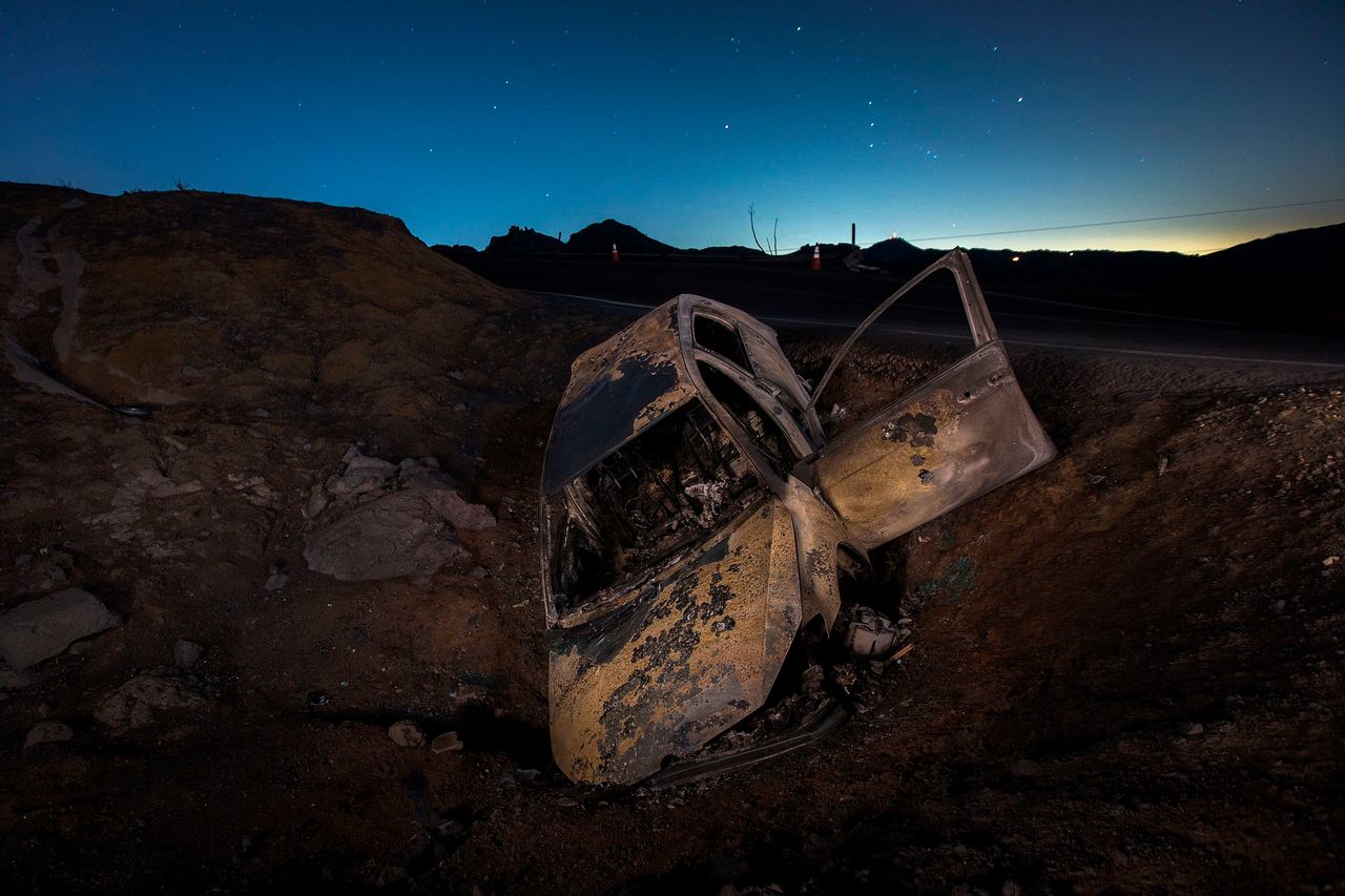 A burned car is seen crashed off the side of Mulholland Highway at night in the Santa Monica Mountains in the aftermath of the Woolsey Fire on 14 November.