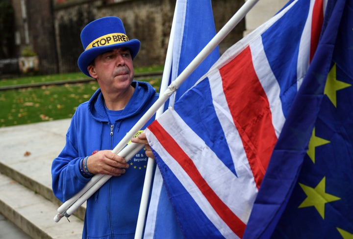 An anti-Brexit demonstrator holds a European Union flag and a British Union flag, also known as a Union Jack, in London Thurs
