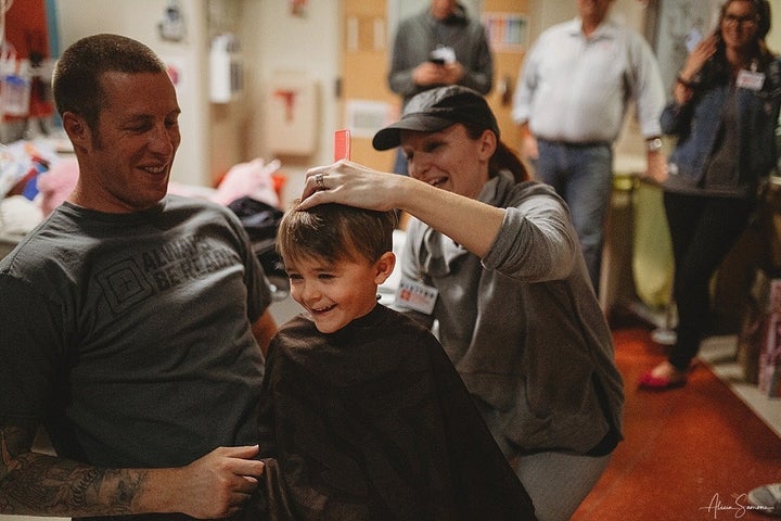 Madi's father, Chris, and her brother sit down for haircuts to show support after acute myeloid leukemia treatment caused her