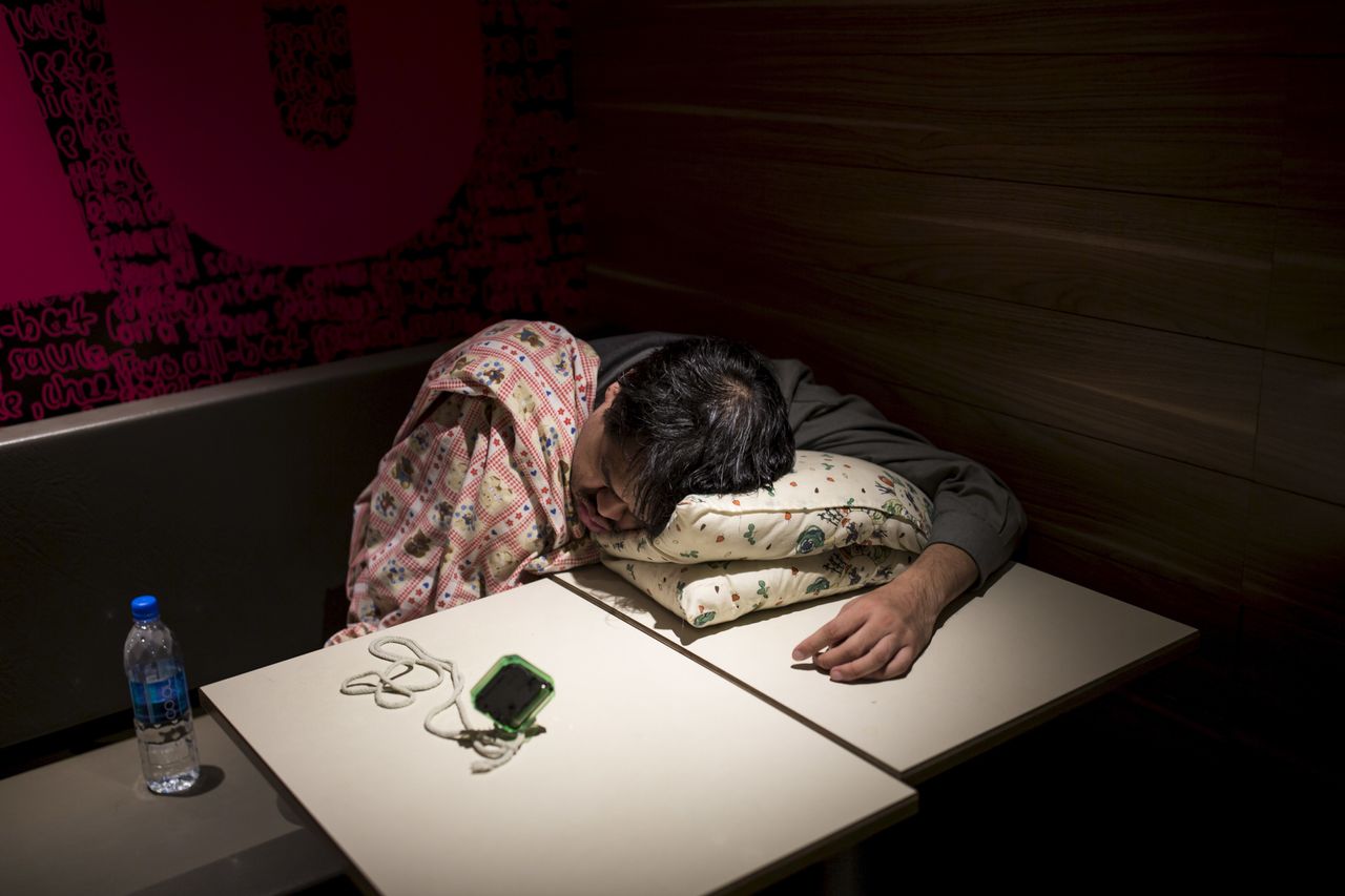 One of Hong Kong's McRefugees sleeps at a 24-hour McDonald's with an alarm clock nearby to wake him up.