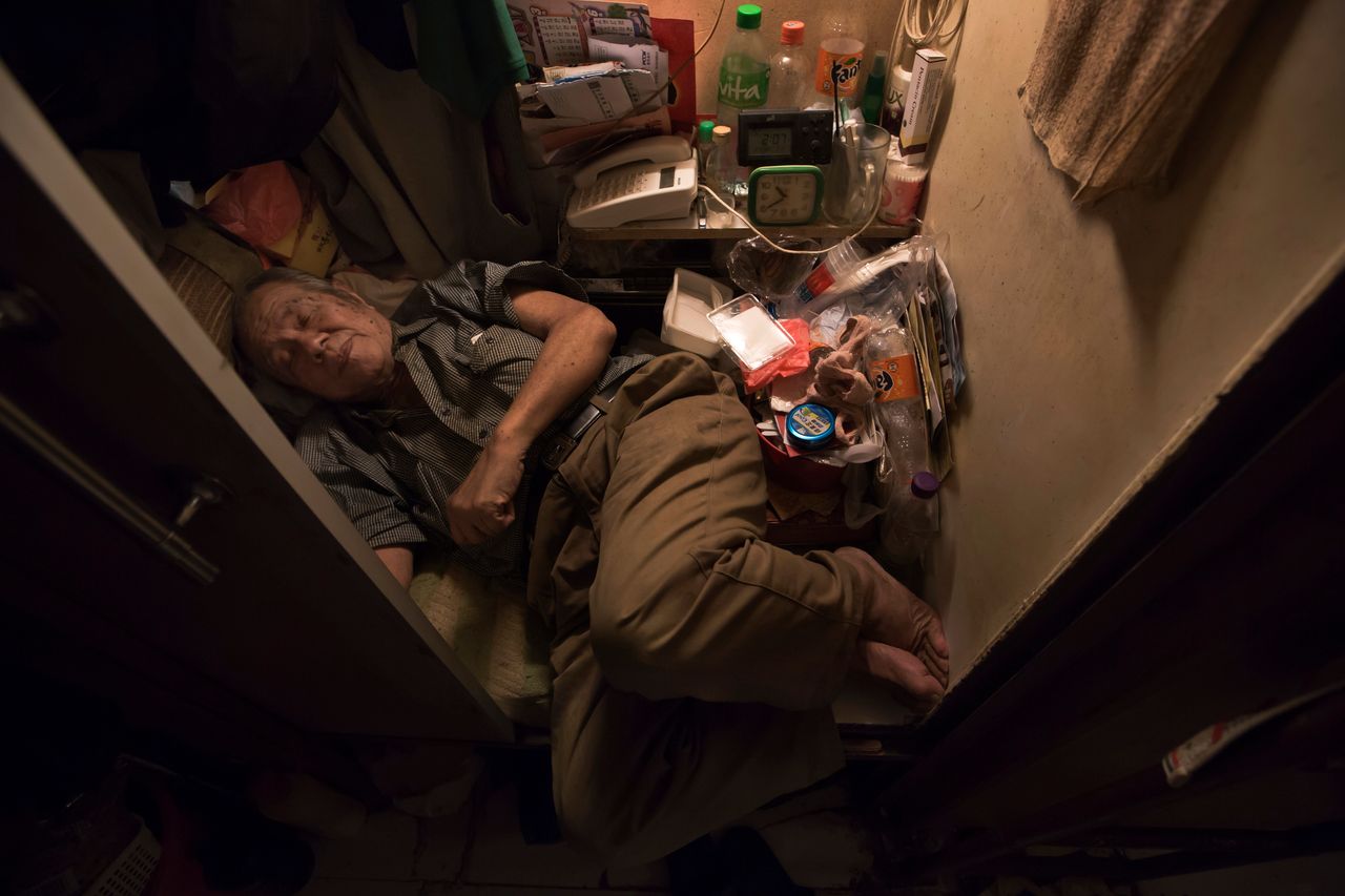 Cheung Chi-fong, 80, sleeps in his tiny "coffin cubicle," where he cannot stretch out his legs.