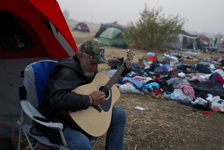 Camp Fire evacuee Kelly Boyer plays guitar in front of his tent next to a Walmart parking on 16 November.