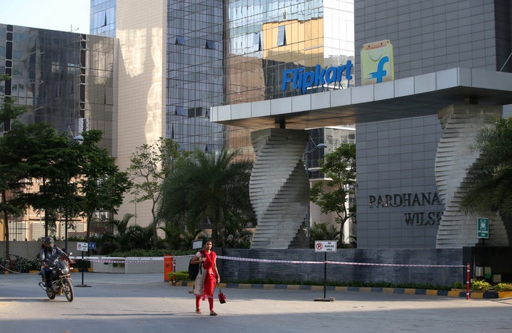 A motorist and a woman walks past a building that formerly was the Flipkart headquarters in Bangalore, India, Wednesday, May
